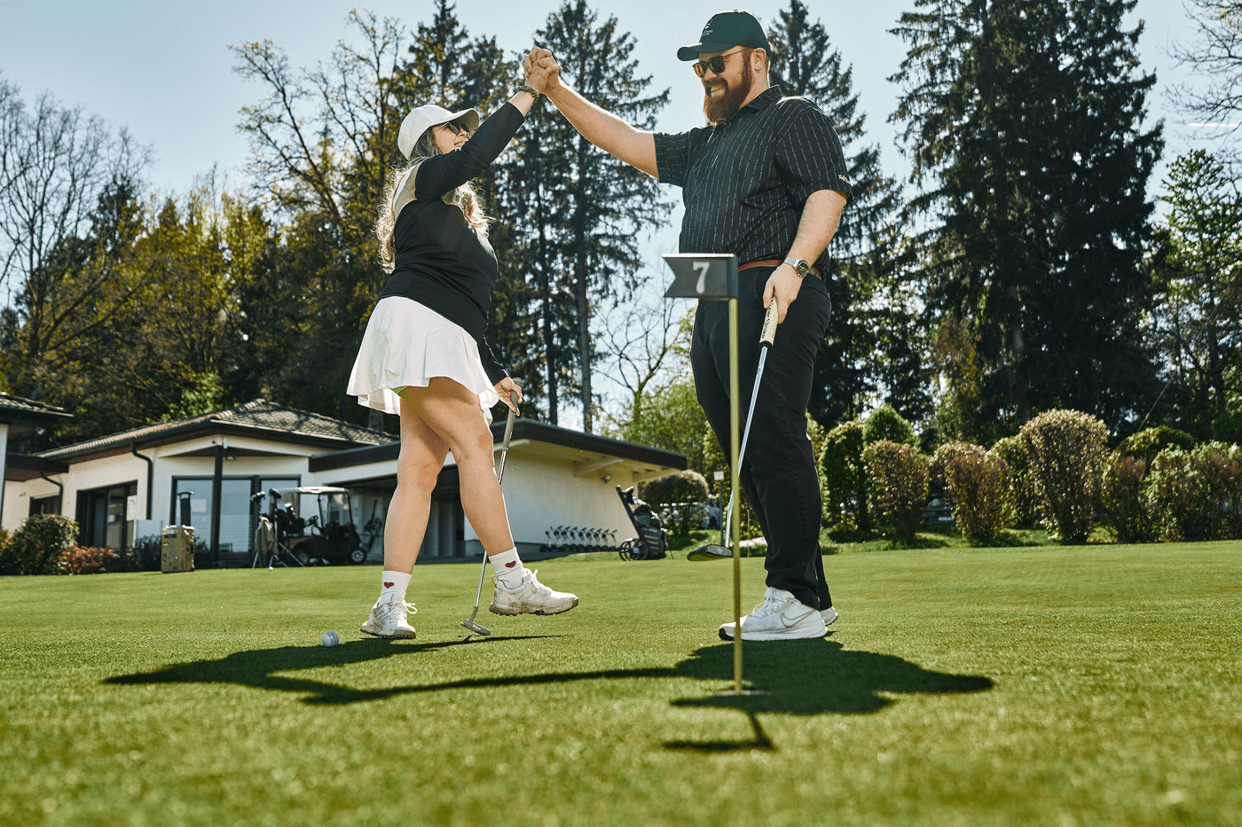 Golfplatzfreude: Zwei Spieler klatschen nach einem erfolgreichen Putt auf Grün Loch 7 ab