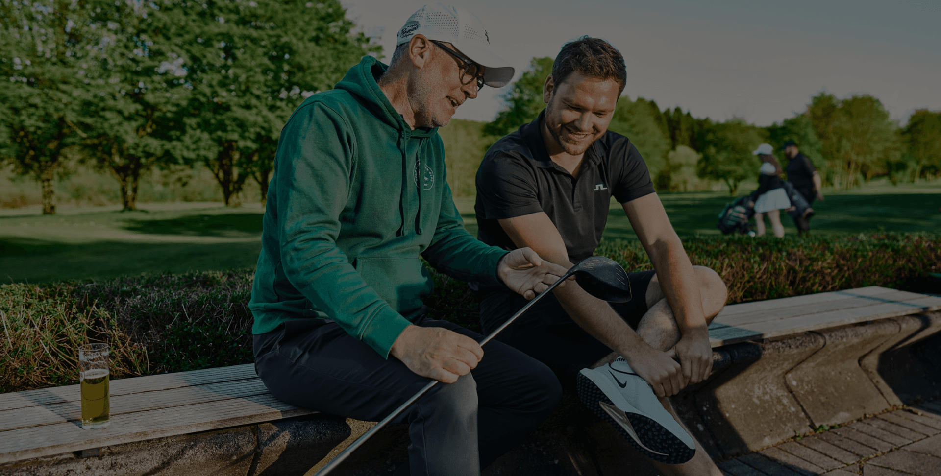 Golftrainer berät Schüler auf der Bank, Golfschläger im Fokus