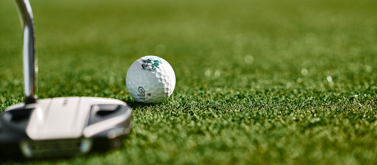 Golfschläger und Ball auf gepflegtem Grün, bereit für den Schlag