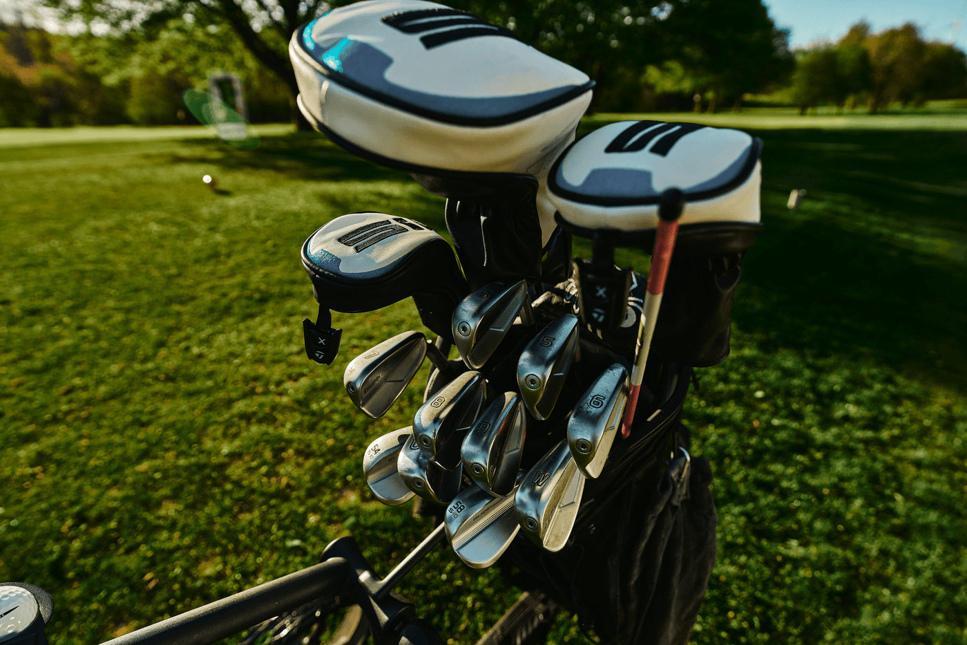 Golfset im Sonnenlicht auf gepflegtem Rasen.